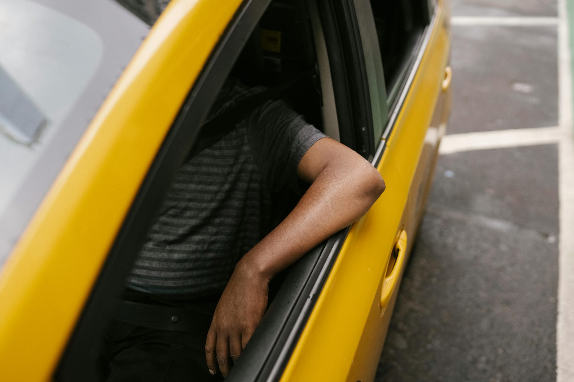 From above of crop anonymous ethnic male working in taxi in modern city
